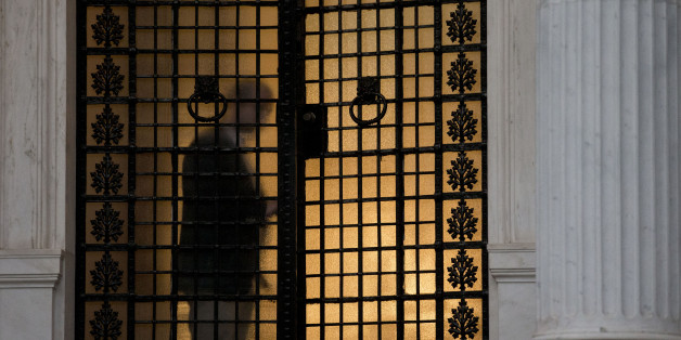 An employee of the Maximos Mansion, the Greek Prime Minister's office in central Athens, closes the door, on Monday, June 15, 2015. As concern over Greece's financial future swelled across financial markets and the two sides quarreled over who's to blame for the current standoff, Prime Minister Alexis Tsipras called an emergency meeting with his team of bailout negotiators. (AP Photo/Petros Giannakouris)