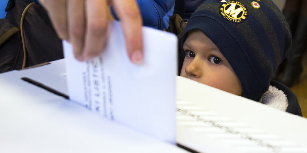 A child looks at a ballot being cast at a polling station in Zagreb, Croatia, Sunday, Nov. 8, 2015. Croatia's ruling center-left coalition faces a strong challenge from a conservative opposition in the Balkan country's first parliamentary election since joining the European Union in 2013. (AP Photo/Darko Bandic)