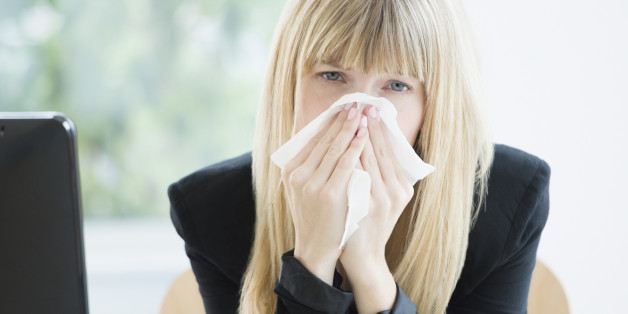 Businesswoman blowing nose in office