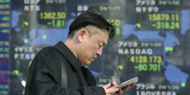 A man walks by an electronic stock board of a securities firm in Tokyo, Monday, Jan. 27, 2014. Asian stock markets tumbled Monday as investors factored in the possibility of slowing growth in China and a further reduction in U.S. central bank stimulus. Japan's Nikkei 225 sank 2.6 percent to 14,993.89 as investors sought out havens such as the Japanese yen, causing it to rise against the dollar which is negative for export stocks. (AP Photo/Koji Sasahara)