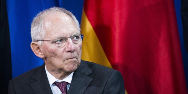 German Finance Minister Wolfgang Schaeuble listens to the German Chancellor as the German Council of Economic Experts (GCEE) Annual Economic Report is presented at the Chancellery in Berlin on November 11, 2015. Germany could spent up to 14.3 billion euros next year for the reception and integration of refugees, but is able to cope with this load, predict the 'Wise Men', a panel of influential economists who advise the German government. AFP PHOTO / ODD ANDERSEN (Photo credit should read