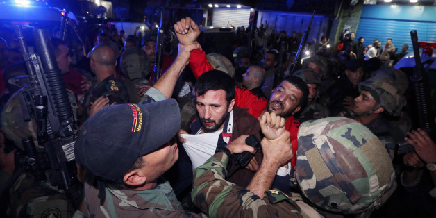 Lebanese soldiers arrest a suspected attacker attacker near the scene of a twin suicide attack in Burj al-Barajneh, southern Beirut, Lebanon, Thursday, Nov. 12, 2015 that struck a Shiite suburb killed and wounded dozens, according to a Lebanese official. (AP Photo/Bilal Hussein)
