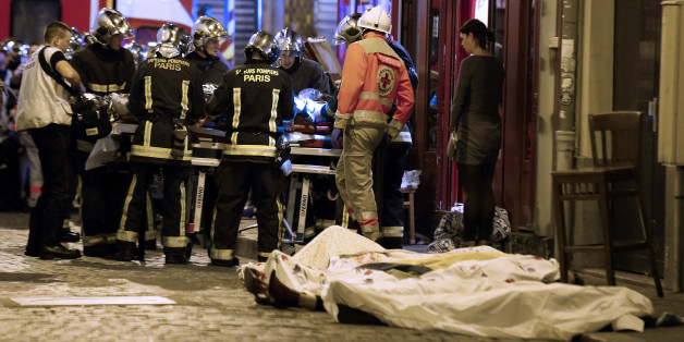 Rescue workers gather at victims in the 10th district of Paris, Friday, Nov. 13, 2015. Several dozen people were killed in a series of unprecedented attacks around Paris on Friday, French President Francois Hollande said, announcing that he was closing the country's borders and declaring a state of emergency. (AP Photo/Jacques Brinon)