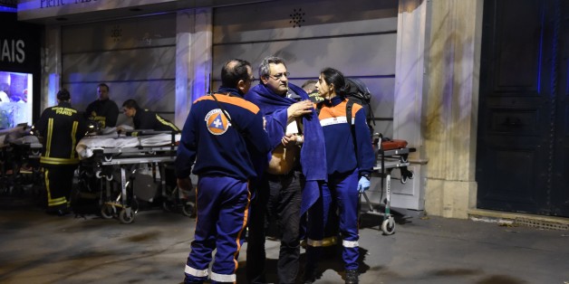 Rescuers assist an injured man on Boulevard des Filles du Calvaire, close to the Bataclan concert hall in central Paris, early on November 14, 2015. A number of people were killed in an 'unprecedented' series of bombings and shootings across Paris and at the Stade de France stadium on November 13, and the death toll looked likely to rise as sources said dozens had been killed at the Bataclan popular music venue. AFP PHOTO / MIGUEL MEDINA (Photo credit should read MIGUEL MEDINA/AFP/Getty I
