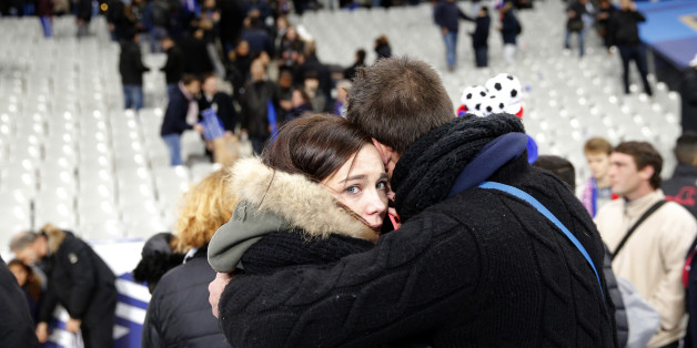 Spectators embrace each other as they stand on the playing field of the Stade de France stadium at the end of a friendly soccer match between France and Germany in Saint Denis, outside Paris, Friday, Nov. 13, 2015. Hundreds made their way to the pitch after explosions were heard nearby. Multiple fatal attacks throughout the city have prompted President Francois Hollande to announce he was closing the country's borders and declaring a state of emergency. (AP Photo/Christophe Ena)