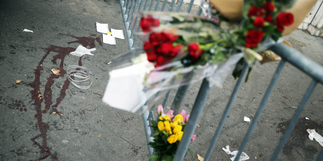Flowers are placed outside the Bataclan concert hall, Saturday, Nov. 14, 2015 in Paris. French President Francois Hollande said more than 120 people died Friday night in shootings at Paris cafes, suicide bombings near France's national stadium and a hostage-taking slaughter inside a concert hall. (AP Photo/Christophe Ena)