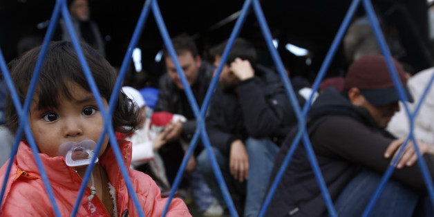 A migrant girl looks through the fence waiting to board a train at the train station in Sid, about 100 km west from Belgrade, Serbia, Wednesday, Nov. 11, 2015. Slovenia on Wednesday began erecting a razor-wire fence along its border with Croatia to control the influx of migrants, as European and African leaders gathered in Malta to seek long-term solutions to the flow of people making their way across Europe. (AP Photo/Darko Vojinovic)
