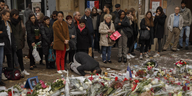 A Muslim, center, prays in front of a floral tributes near the Bataclan concert hall after the terrorist attacks in Paris, Monday, Nov. 16, 2015.