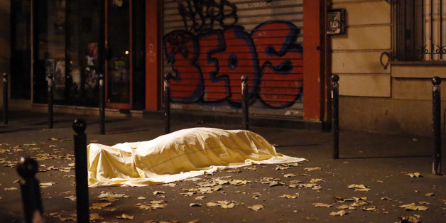 FILE - In this Friday, Nov. 13, 2015, file photo, a victim of an attack in Paris lays dead outside the Bataclan theater, Paris, Friday Nov. 13, 2015. Coming soon after the Islamic State group claimed the downing of the Russian plane in Egypt and deadly suicide bombings in Lebanon and Turkey, the Paris attacks appear to signal a fundamental shift in strategy toward a more global approach that experts suggest is likely to intensify. (AP Photo/Jerome Delay, File)