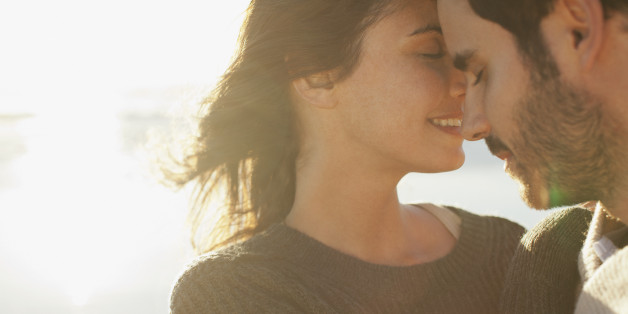 Sun shining behind couple hugging with eyes closed