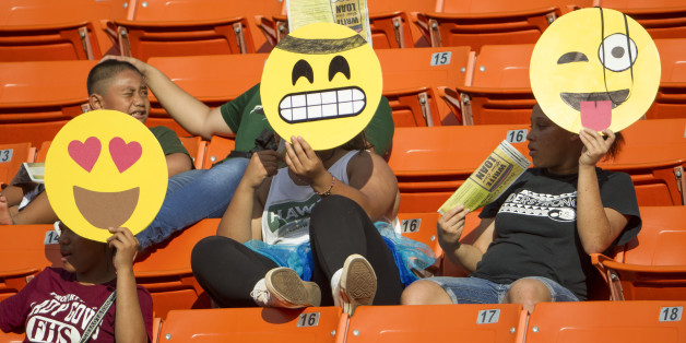 These Hawaii fans hold their emoji character mask in celebration of Halloween before the start of an NCAA college football game between Air Force and Hawaii, Saturday, Oct. 31, 2015, in Honolulu. (AP Photo/Eugene Tanner)