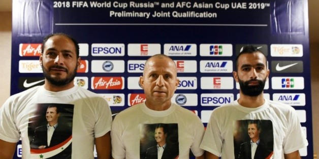 Fajr Ibrahim (c), le sélectionneur de l'équipe de foot de Syrie, et le joueur Osama Omari (d) posent avec des T-shirts à l'effigie du président Bachar al-Assad en conférence de presse le 16 novembre 2015 à Singapour