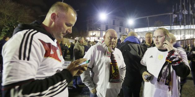 German soccer fans stand outside the stadium as the soccer friendly match between Germany and the Netherlands was cancelled in Hannover, Germany, Tuesday, Nov. 17, 2015. (AP Photo/Markus Schreiber)