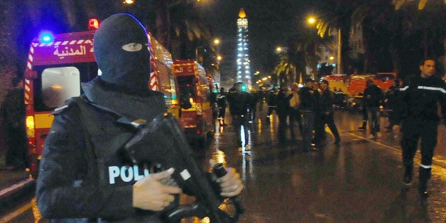 A hooded police officer prevents media from aproaching the scene of a bus explosion in the center of the capital, Tunis, Tunisia, Tuesday, Nov. 24, 2015. An explosion struck a bus carrying members of Tunisia's presidential guard in the country's capital Tuesday, killing at least 12 people and wounding more than a dozen others in what the Interior Ministry called a "terrorist act". (AP Photo/Hassene Dridi)