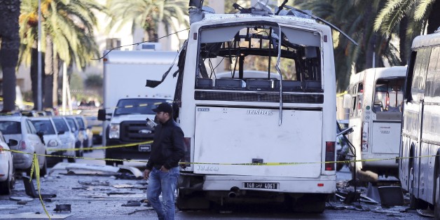 A man walks past the bus that exploded Tuesday in Tunis, Wednesday Nov.25, 2015. Tunisia's president declared a 30-day state of emergency across the country and imposed an overnight curfew for the capital Tuesday after an explosion struck a bus carrying members of the presidential guard, killing at least 12 people and wounding 20 others. (AP Photo)