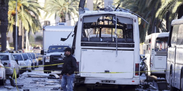 A man walks past the bus that exploded Tuesday in Tunis, Wednesday Nov.25, 2015. Tunisia's president declared a 30-day state of emergency across the country and imposed an overnight curfew for the capital Tuesday after an explosion struck a bus carrying members of the presidential guard, killing at least 12 people and wounding 20 others. (AP Photo)