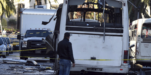 A plainclothes police officer walks beside the bus that exploded Tuesday in Tunis, Wednesday Nov.25, 2015. Tunisia's Interior Ministry says 10 kilograms (22 pounds) of military explosives were used in an attack on a bus carrying presidential guards that left at least 13 people dead. (AP Photo)
