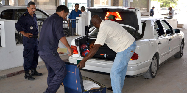 Tunisian custom officers check the luggage of a man fleeing from Libya at the Ras Ajdir border post between Libya and Tunisia, southern Tunisia, Thursday, July 31, 2014. Up to 6,000 people a day have fled Libya into neighboring Tunisia this week, the Tunisian foreign minister said Wednesday, the biggest influx since Libya's 2011 civil war in a sign of the spiraling turmoil as rival militias battle over control of the airport in the capital Tripoli. (AP Photo/Ali Manssour)