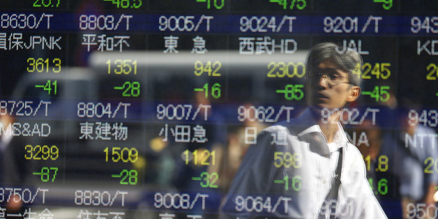 A man is reflected on an electronic stock indicator of a securities firm in Tokyo, Wednesday, Oct. 14, 2015. Asian stock markets extended losses Wednesday following a drop on Wall Street as investors digested weak Chinese trade data and China's low inflation rate.(AP Photo/Shizuo Kambayashi)