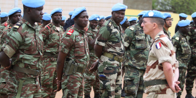 A French soldier stands alongside African troops who helped France take back Mali's north earlier this year, as they participate in a ceremony formally transforming the force into a United Nations peacekeeping mission, in Bamako, Mali, Monday, July 1, 2013. The roughly 6,000 African troops will be folded into the Integrated United Nations Mission for the Stabilization of Mali, or MINUSMA, which is expected to grow to more than 12,000 soldiers. (AP Photo/Harouna Traore)
