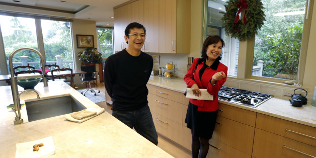 Janie Lee, right, a residential specialist with John L. Scott Real Estate, shares a laugh in the kitchen of a home for sale to she was showing to her client, Hongbin Wei, of Beijing, China, Thursday, Dec. 18, 2014, in Medina, Wash., near Seattle. Real estate agents such as Lee are taking note of growing connections linking China and Washington state, which ranks second to California in real estate sales to Chinese buyers. (AP Photo/Ted S. Warren)