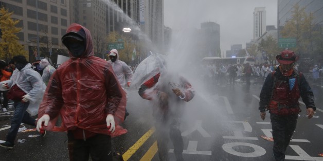 South Korean riot police officers spray water cannons to try to break up protesters who tried to march to the Presidential House after a rally against government policy in Seoul, South Korea, Saturday, Nov. 14, 2015. Police fired tear gas and water cannons Saturday as they clashed with anti-government demonstrators who marched through Seoul in what was believed to be the largest protest in South Korea's capital in more than seven years.(AP Photo/Ahn Young-joon)