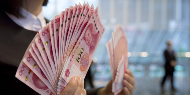 A staff member displays the new version of the 100-yuan RMB banknotes for photographers at the Bank of China Tower in Hong Kong, Thursday, Nov. 12, 2015. China released Thursday a new version of the 100-yuan bill, which bears a golden "100" and adopts advanced anti-counterfeit technology. The "100" on the new bill appears golden from certain angles. (AP Photo/Kin Cheung)