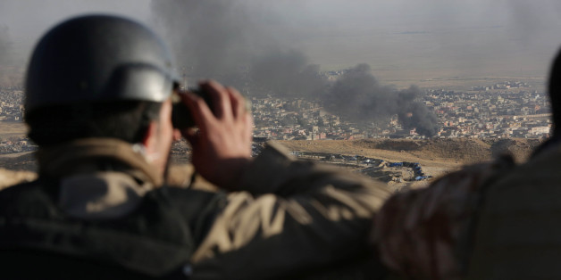 A journalist watches as smoke rises over Sinjar, northern Iraq from oil fires set by Islamic State militants as Kurdish Iraqi fighters, backed by U.S.-led airstrikes, launch a major assault on Thursday, Nov. 12, 2015. The strategic town of Sinjar was overran last year by the Islamic State group in an onslaught that caused the flight of tens of thousands of Yazidis and first prompted the United States to launch the air campaign against the militants. (AP Photo/Bram Janssen)