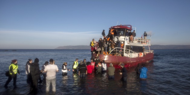 Volunteers help around 150 refugees and migrants, mostly from Syria and Iraq, to disembark from a vessel after their arrival from the Turkish coast to the northeastern Greek island of Lesbos, on Tuesday, Dec. 1, 2015. Authorities in northwestern Turkey on Monday rounded up some 1,300 asylum seekers and migrants allegedly preparing to make their way into Greece. (AP Photo/Santi Palacios)