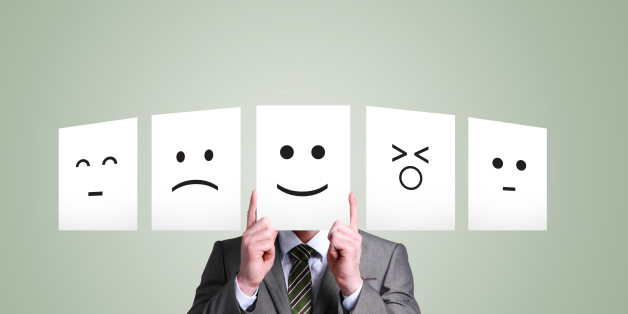 Business man holding up smiley face in front of hi