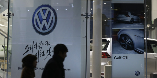 People walk by a logo of Volkswagen at a dealership in Seoul, South Korea, Thursday, Nov. 26, 2015. South Korea said Thursday it fined Volkswagen $12.3 million and ordered recalls of 125,522 diesel vehicles after the government found their emissions tests were rigged. (AP Photo/Ahn Young-joon)