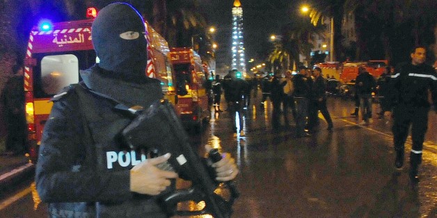 A hooded police officer prevents media from aproaching the scene of a bus explosion in the center of the capital, Tunis, Tunisia, Tuesday, Nov. 24, 2015. An explosion struck a bus carrying members of Tunisia's presidential guard in the country's capital Tuesday, killing at least 12 people and wounding more than a dozen others in what the Interior Ministry called a "terrorist act". (AP Photo/Hassene Dridi)