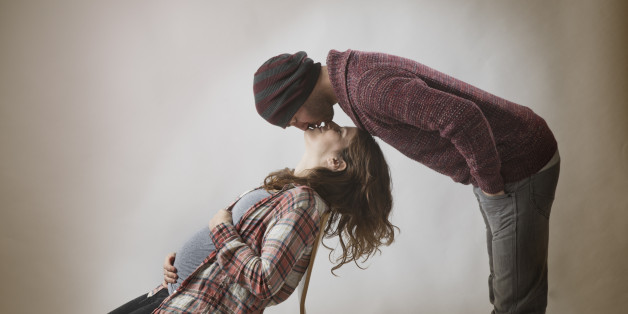 PRegnant couple in chair and kissing