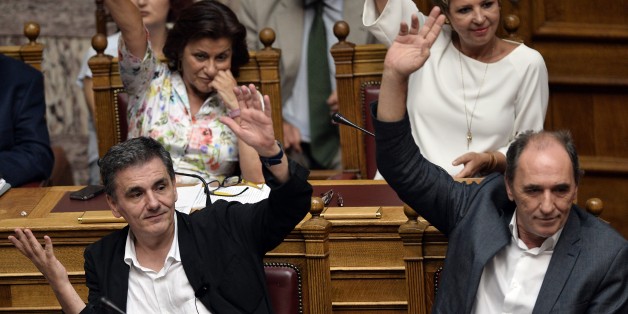 Greek Finance Minister Euclid Tsakalotos (L) and Economy Minister Giorgos Stathakis vote on procedure during a parliamentary debate in Athens early on August 14, 2015. Greek lawmakers held an emergency parliamentary session for a crucial vote on ratifying a hurriedly-concluded bailout deal, but Germany -- Europe's de facto paymaster -- has cast doubt on the agreement. AFP PHOTO / LOUISA GOULIAMAKI (Photo credit should read LOUISA GOULIAMAKI/AFP/Getty Images)