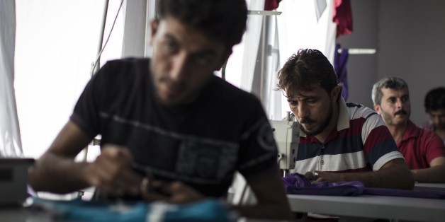SANLIURFA, TURKEY - SEPTEMBER 24: Refugees work at a textile workshop at a tent city in the Akcakale District of Sanliurfa, Turkey on September 24, 2015. Refugees who take classes in weaving, confectionary-making, hairdressing, art etc. at the camp's social facilities are also able to contribute to their family income with the products they produce. 260 thousand Syrians who have escaped war and found asylum in Turkey are now living in camps with opportunities that mean they don't miss what they'