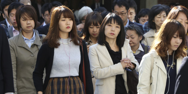 In this Monday, Oct. 26, 2015 photo, commuters cross a street during morning rush hour in Tokyo. The central government exceeded its 30 percent target for hiring of women for career-track positions, raising the rate to 34 percent this year from 24 percent last year, according to the latest Cabinet Office data. Two years after Prime Minister Shinzo Abe made womenâs advancement a top policy priority, statistics suggest Japanâs male-dominated workplaces have evolved slightly, but also hig