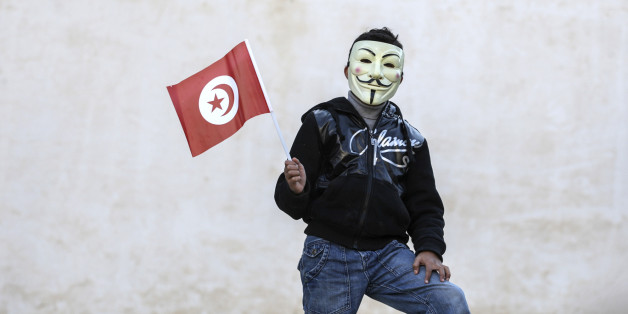 A civilian wearing a mask holds a Tunisian flag in Sidi Bouzid, central Tunisia, Tuesday, Dec. 17, 2013 to mark the third anniversary of the Tunisian uprising. Several political groups gather at the square where Mohamed Bouazizi's self-immolation on Dec. 17, 2010 triggered mass protests against social marginalisation and government corruption in Tunisia. (AP Photo/Aimen Zine)