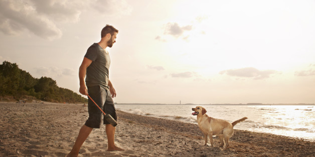 Man playing with dog by the sea