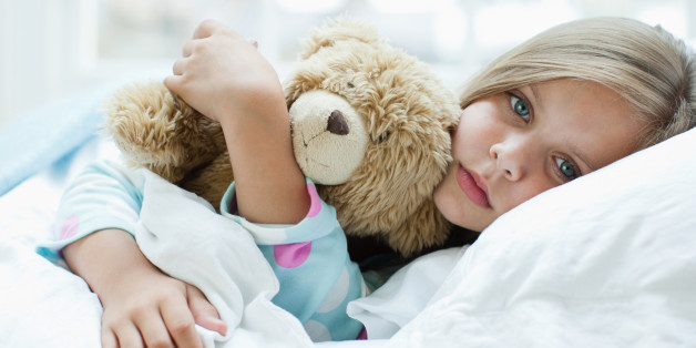 Sick girl laying in bed with teddy bear