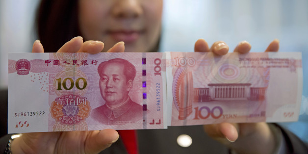 A staff member displays the new version of the 100-yuan RMB banknotes (US 15.7 dollars) to photographers at the Bank of China Tower in Hong Kong, Thursday, Nov. 12, 2015. China released Thursday a new version of the 100-yuan bill, which bears a golden "100" and adopts advanced anti-counterfeit technology. The "100" on the new bill appears golden from certain angles. (AP Photo/Kin Cheung)