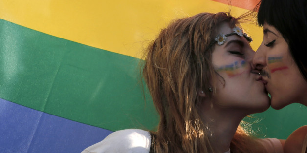FILE - In this Saturday, June 14, 2014 file photo, two women kiss in front of a rainbow flag, the symbol of the gay rights movement, during the Gay Pride parade in central Athens. Around the globe, LGBT Pride Month has been marked with parades and marches, festivals and dances, and in some cases, protests and counter-protests. (AP Photo/Petros Giannakouris, File)