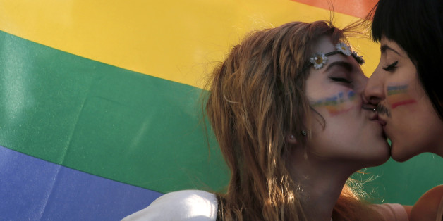 FILE - In this Saturday, June 14, 2014 file photo, two women kiss in front of a rainbow flag, the symbol of the gay rights movement, during the Gay Pride parade in central Athens. Around the globe, LGBT Pride Month has been marked with parades and marches, festivals and dances, and in some cases, protests and counter-protests. (AP Photo/Petros Giannakouris, File)
