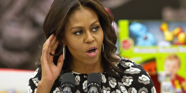 First lady Michelle Obama listens for a shout out from members of the military as she speaks before sorting toys as part of the Marine Corps Toys for Tots program, Wednesday, Dec. 9, 2015, at Bolling Air Force Base in Washington. (AP Photo/Jacquelyn Martin)