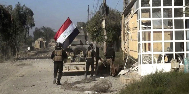 Iraqi security forces hold a national flag as they enter the southern neighborhoods of Ramadi, 70 miles (115 kilometers) west of Baghdad, Iraq, Wednesday, Dec. 23, 2015. Iraqi security forces' advance was slowed by snipers, roadside bombs and booby trapped buildings, military spokesman Brig. Gen. Yahya Rasool, told The Associated Press. Rasool said some of the families that were trapped in Ramadi had managed to flee the city and reached safe areas. (AP Photo)