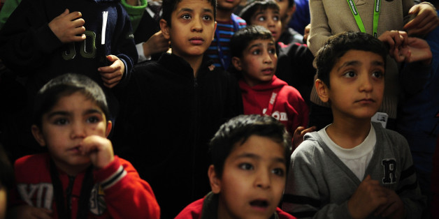 SARSTEDT, GERMANY - DECEMBER 24: Children from Syria and Afghanistan look at a volunteer dressed as Santa Claus while greeting them at a shelter for migrants and refugees on December 24, 2015 in Sarstedt, Germany. Thousands of Germans have volunteered in recent months at migrant shelters across the country as Germany seeks to cope with an influx of what will likely be over one million asylum-applicants by the end of 2015. (Photo by Alexander Koerner/Getty Images)