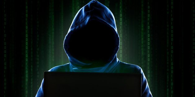 Faceless hooded anonymous computer hacker with programming digital code from monitor.