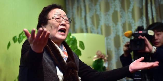 South Korean former sex slave Lee Yong-su makes a gesture of protest at South Korean First Vice Foreign Minister Lim Sung-nam during his visit to a shelter for women, who were forced into Japanese military-run brothels during World War II, in Seoul, Tuesday, Dec. 29, 2015. South Korean officials met with former sex slaves to seek their support for a landmark deal with Japan. (Jung Yeon-je/Pool Photo via AP)