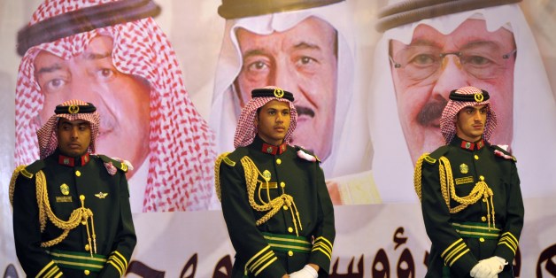 FILE - In this Feb. 18, 2014 file photo, Saudi royal guards stand on duty in front of portraits of King Abdullah bin Abdulaziz, right, then Crown Prince Salman bin Abdulaziz, center, and Muqrin bin Abdulaziz during a culture festival in Riyadh, Saudi Arabia. WikiLeaks is in the process of publishing more than 500,000 Saudi diplomatic documents to the Internet, the transparency website said Friday, June 19, 2015. If genuine, the documents would offer a rare glimpse into the inner workings of the