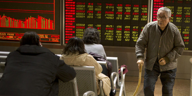 A Chinese investor walks through a brokerage house in Beijing, Friday, Dec. 4, 2015. Asian stocks sank Friday, extending a sell-off in world markets after Europe's central bank unveiled plans to stimulate the continent's ailing economy that fell short of investor expectations. (AP Photo/Mark Schiefelbein)
