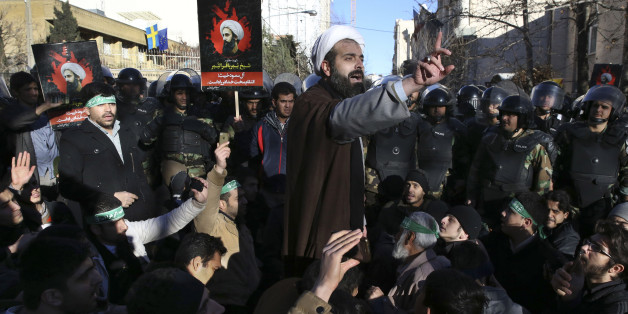 Surrounded by policemen, a Muslim cleric addresses a crowd during a demonstration to denounce the execution of Saudi Shiite Sheikh Nimr al-Nimr, seen in poster, in front of the Saudi embassy in Tehran, Iran, Sunday, Jan. 3, 2016. Saudi Arabia announced the execution of al-Nimr on Saturday along with 46 others. Al-Nimr was a central figure in protests by Saudi Arabia's Shiite minority until his arrest in 2012, and his execution drew condemnation from Shiites across the region. (AP Photo/Vahid Salemi)